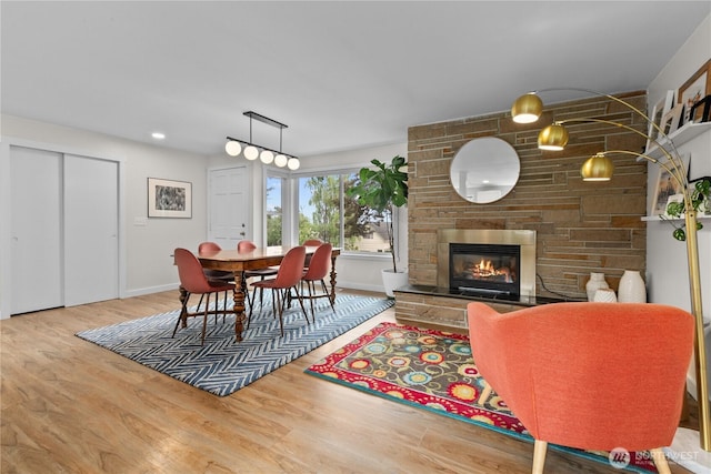 dining space featuring a stone fireplace, baseboards, and wood finished floors
