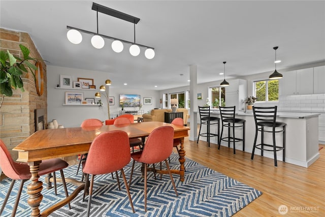 dining room with light wood-type flooring and a fireplace