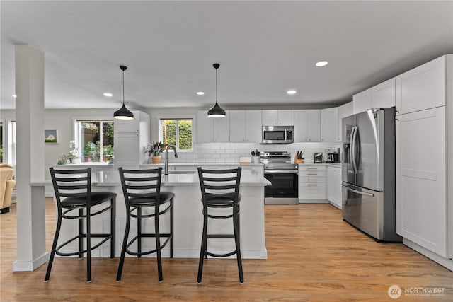 kitchen featuring stainless steel appliances, a breakfast bar, a center island with sink, and tasteful backsplash
