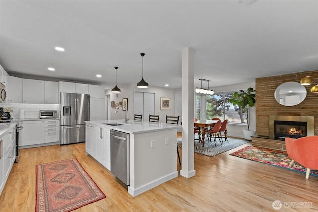 kitchen featuring a sink, light wood finished floors, appliances with stainless steel finishes, and light countertops