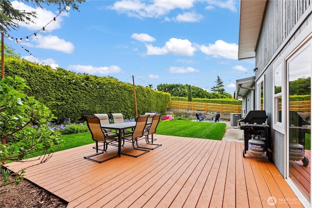 deck featuring area for grilling, central AC unit, a fenced backyard, a yard, and outdoor dining space