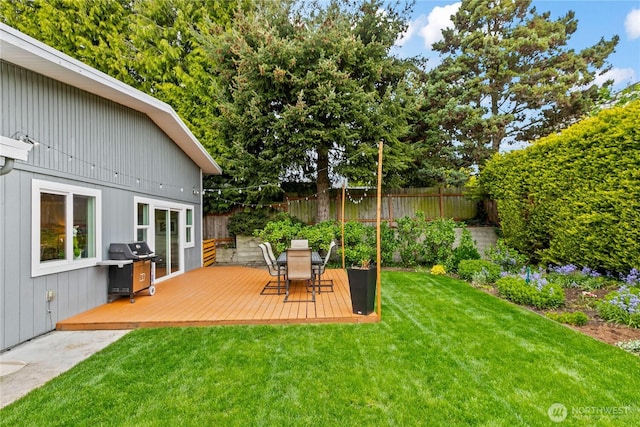 view of yard featuring a deck, outdoor dining area, and a fenced backyard