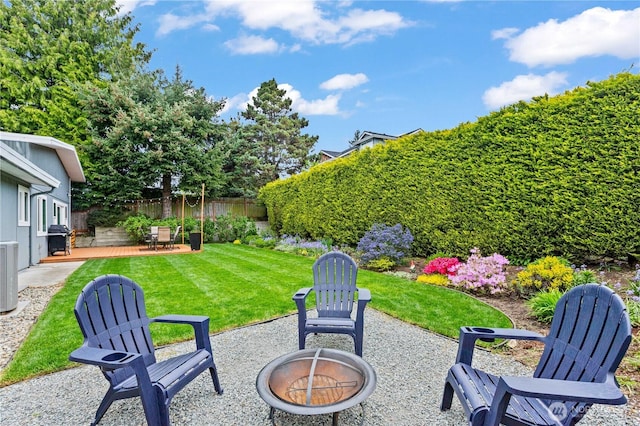 view of yard with a deck, a fenced backyard, a patio area, central air condition unit, and a fire pit