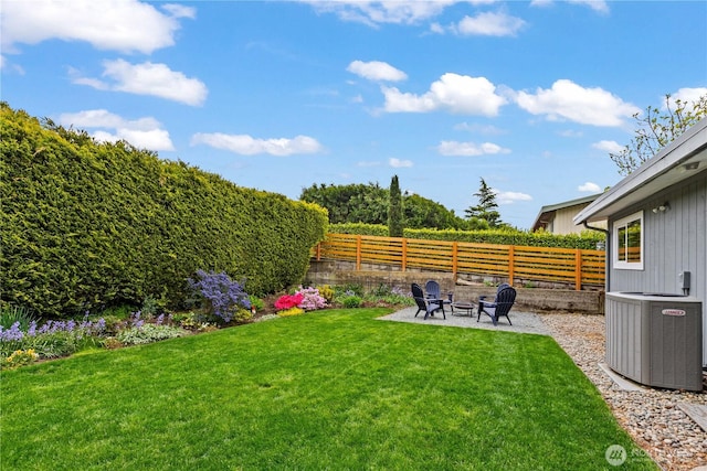 view of yard with a patio, a fenced backyard, an outdoor fire pit, and central air condition unit