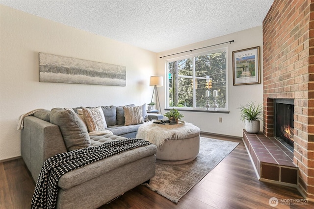 living area with baseboards, a textured ceiling, wood finished floors, and a fireplace