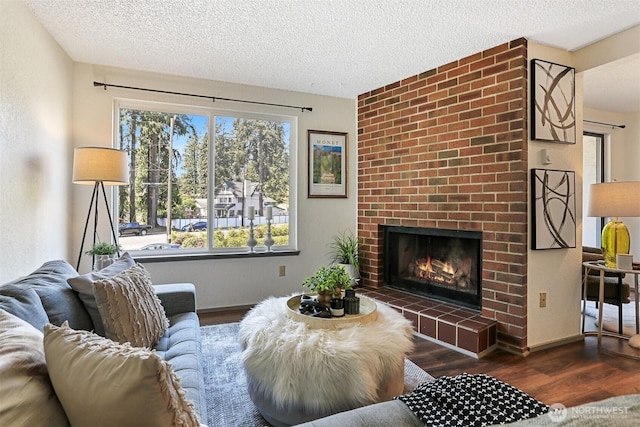 living room featuring a textured ceiling, baseboards, a fireplace, and wood finished floors