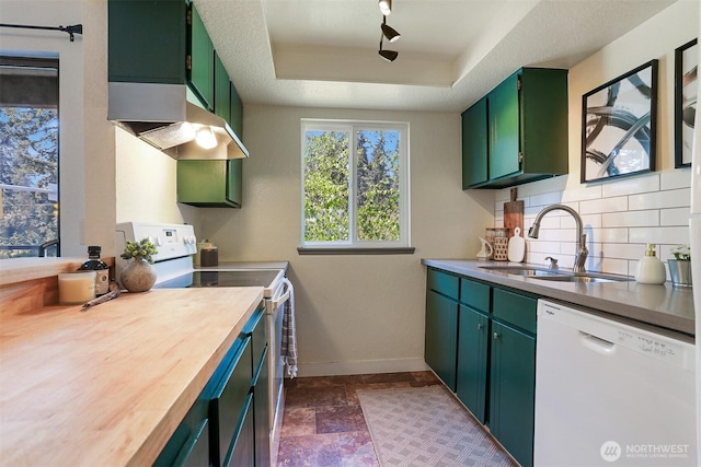 kitchen with tasteful backsplash, a sink, baseboards, green cabinets, and white appliances