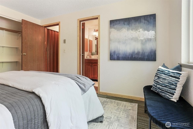 bedroom featuring a textured ceiling, baseboards, and ensuite bath