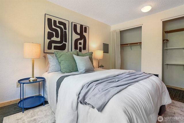 bedroom featuring a closet, a textured ceiling, baseboards, and wood finished floors