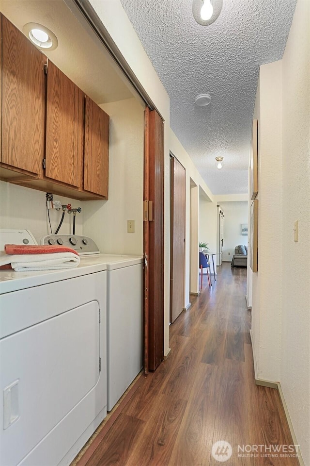 laundry area featuring separate washer and dryer, a textured ceiling, cabinet space, and dark wood-style floors