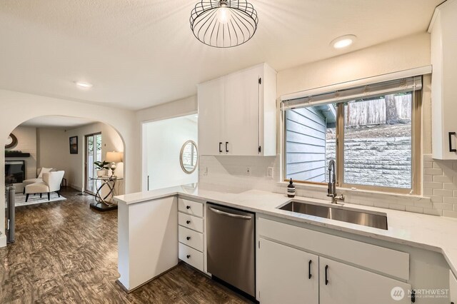 kitchen featuring stainless steel dishwasher, arched walkways, white cabinets, tasteful backsplash, and a sink