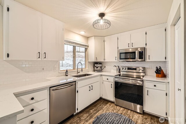 kitchen with a sink, white cabinets, stainless steel appliances, and dark wood finished floors