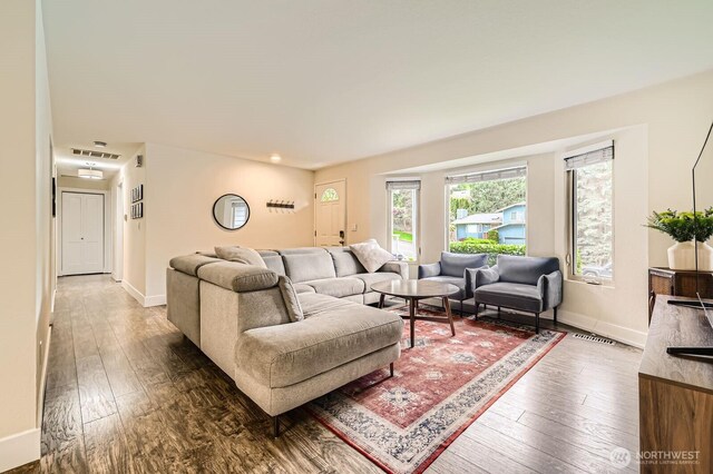 living room with baseboards, visible vents, and hardwood / wood-style flooring