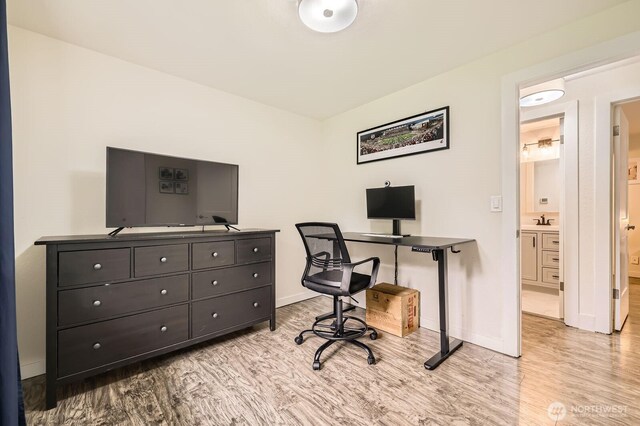 office with baseboards, a sink, and light wood-style flooring