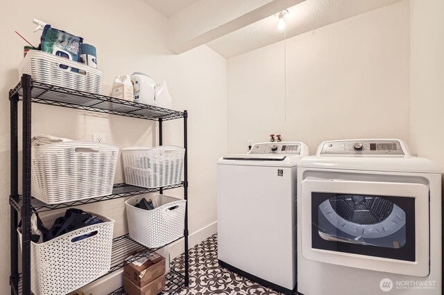 clothes washing area featuring laundry area, baseboards, and washer and dryer