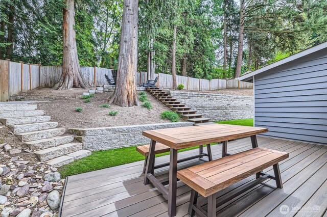 deck with stairs, a fenced backyard, and outdoor dining space