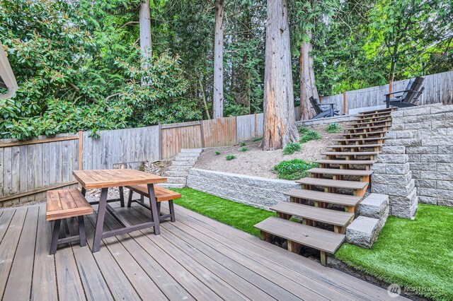 wooden terrace featuring stairway, outdoor dining area, and a fenced backyard