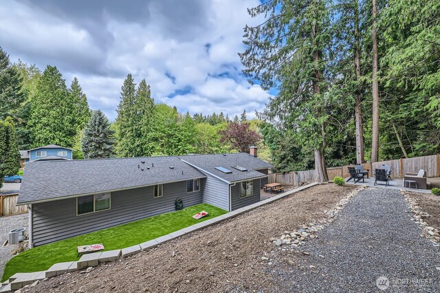 back of house featuring a patio area, cooling unit, a fenced backyard, a yard, and a shingled roof