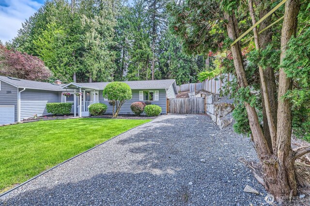 ranch-style house with fence, gravel driveway, and a front lawn