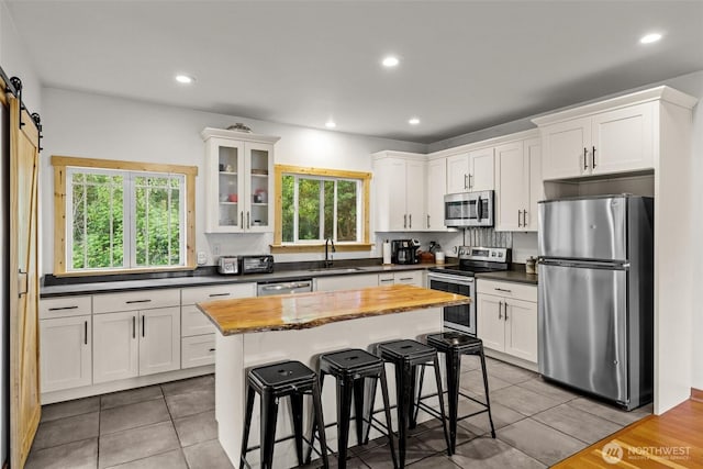 kitchen with a sink, white cabinets, appliances with stainless steel finishes, and a healthy amount of sunlight