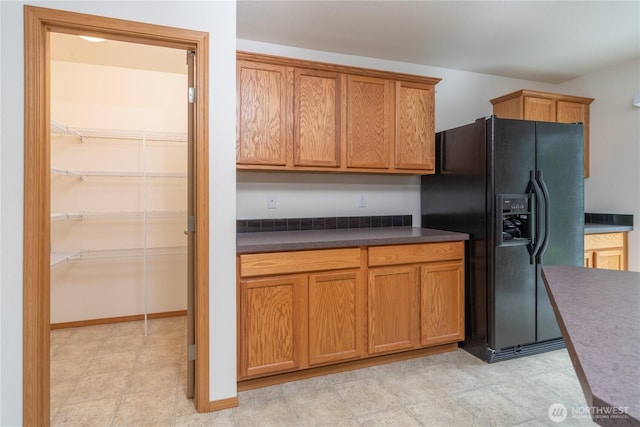 121 George Leslie Dr, Port Ludlow, WA 98365 - kitchen with black fridge with ice dispenser, dark countertops, and brown cabinets