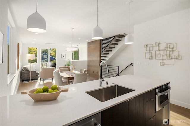 7356 21st Ave NW, Seattle, WA 98117 - kitchen featuring dark brown cabinetry, a sink, light countertops, decorative light fixtures, and open floor plan