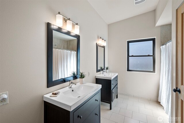 full bathroom featuring baseboards, visible vents, two vanities, and a sink