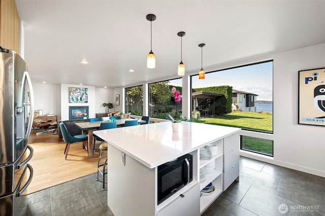 kitchen featuring black microwave, modern cabinets, light countertops, stainless steel fridge with ice dispenser, and recessed lighting