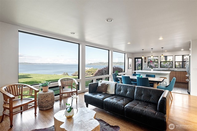living area featuring light wood-style floors, recessed lighting, and a water view