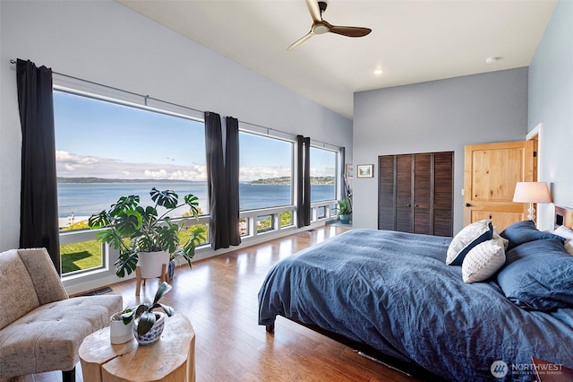 bedroom with a water view, a ceiling fan, recessed lighting, and wood finished floors