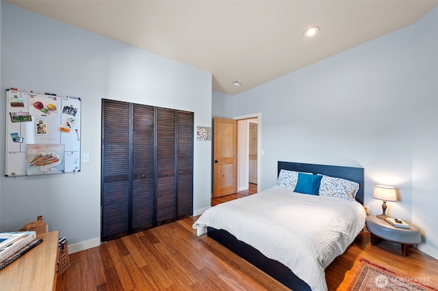 bedroom with recessed lighting, baseboards, wood finished floors, and a closet