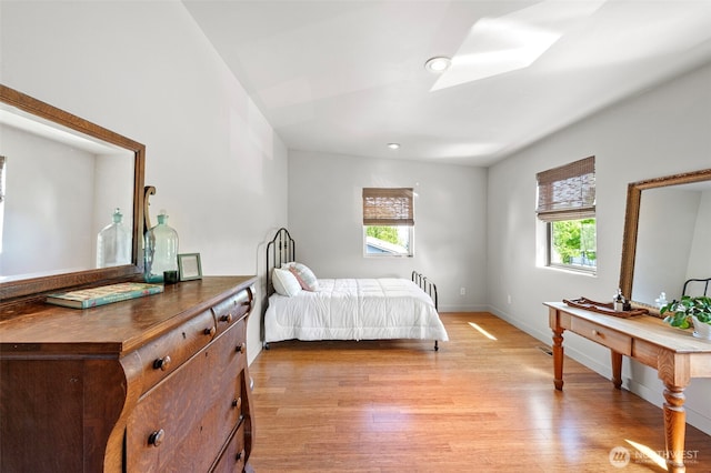 bedroom with baseboards, multiple windows, and light wood-type flooring