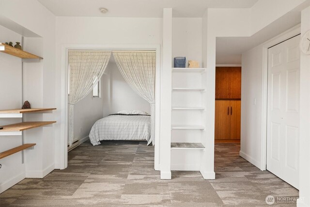 bedroom with wood finished floors, baseboards, and an AC wall unit