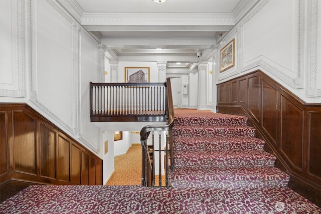 staircase featuring a decorative wall, crown molding, carpet floors, and beam ceiling