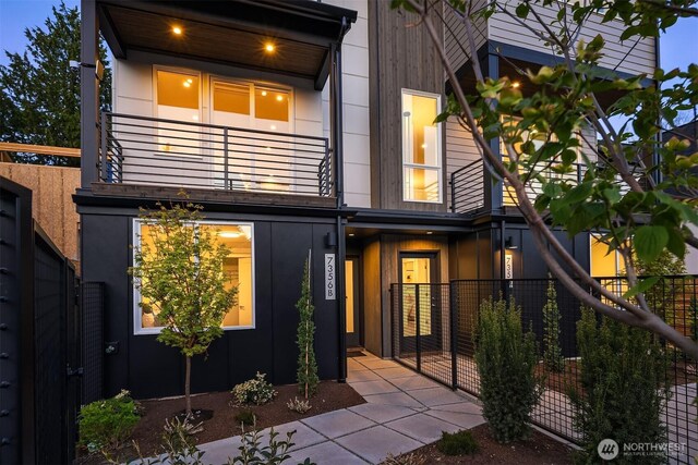 back of property with fence, a gate, and a balcony