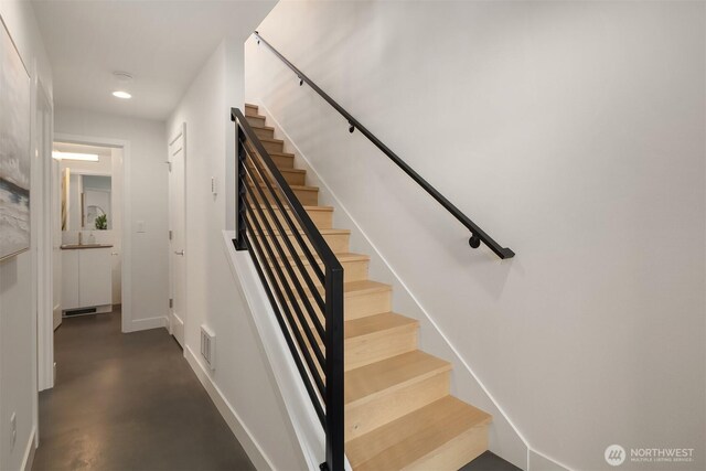stairs featuring finished concrete floors, recessed lighting, baseboards, and visible vents