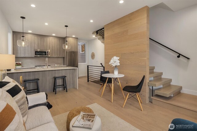 living area featuring stairs, recessed lighting, and light wood finished floors
