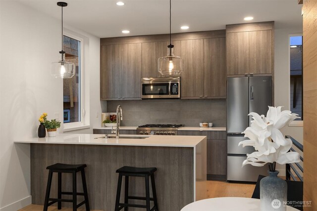 kitchen with a sink, modern cabinets, stainless steel appliances, and a kitchen breakfast bar