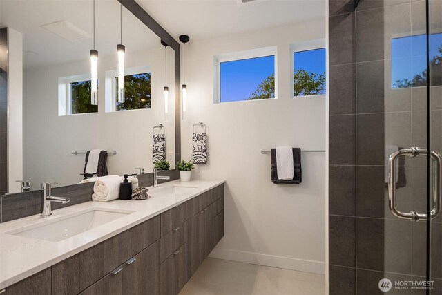 bathroom featuring double vanity, baseboards, a shower stall, and a sink