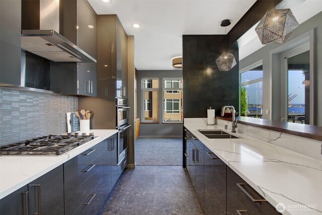 kitchen with decorative backsplash, baseboards, wall chimney exhaust hood, a sink, and appliances with stainless steel finishes