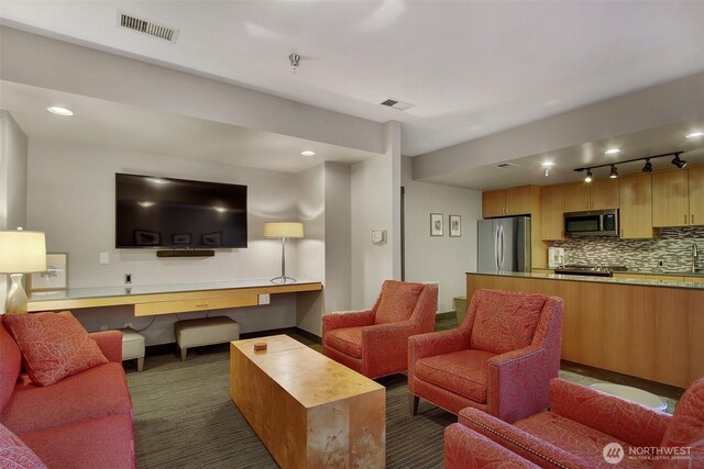 living room with baseboards, dark colored carpet, rail lighting, and visible vents