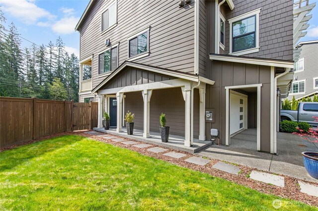 exterior space with board and batten siding, a yard, fence, and covered porch
