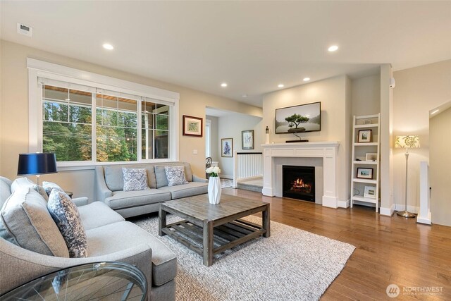 living area featuring a lit fireplace, visible vents, wood finished floors, baseboards, and recessed lighting