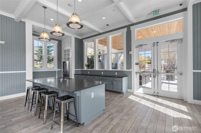 kitchen featuring dark countertops, a sink, beam ceiling, and light wood-type flooring