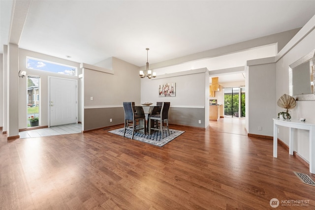 dining room featuring baseboards, a notable chandelier, visible vents, and wood finished floors