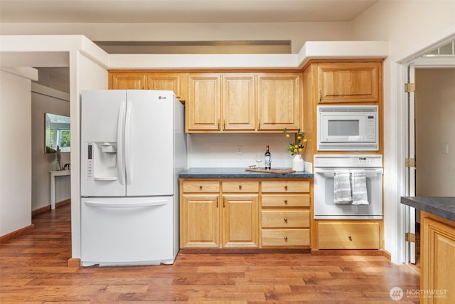 kitchen with white appliances, dark countertops, and light wood-style flooring