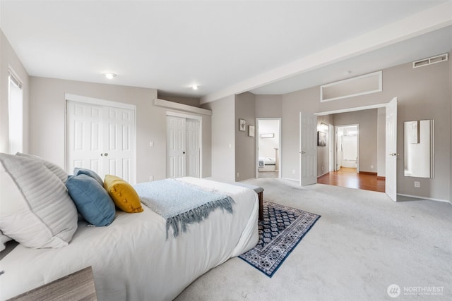 carpeted bedroom with multiple closets, visible vents, baseboards, and ensuite bath