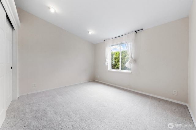 spare room with baseboards, carpet, and lofted ceiling