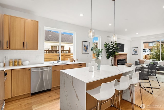 8018 24th Ave NW, Seattle, WA 98117 - kitchen with stainless steel dishwasher, light wood finished floors, a sink, a fireplace, and a center island