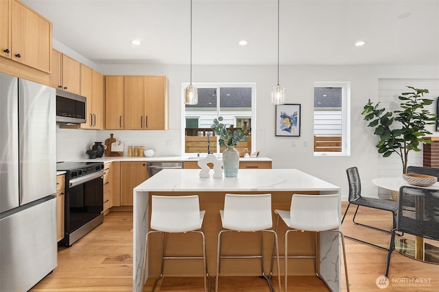 8018 24th Ave NW, Seattle, WA 98117 - kitchen featuring stainless steel appliances, light brown cabinetry, a breakfast bar area, light wood finished floors, and recessed lighting